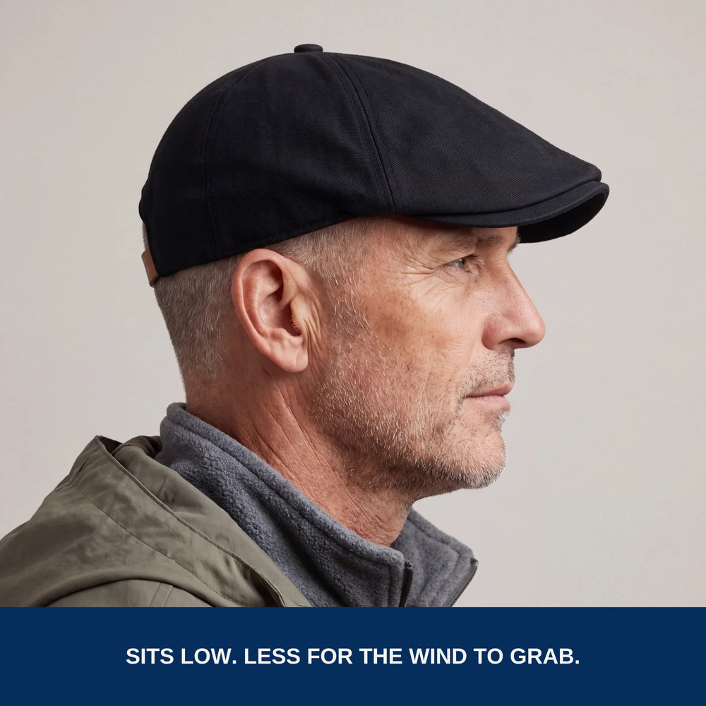 Side profile of the black flat cap worn low. Less for the wind to grab