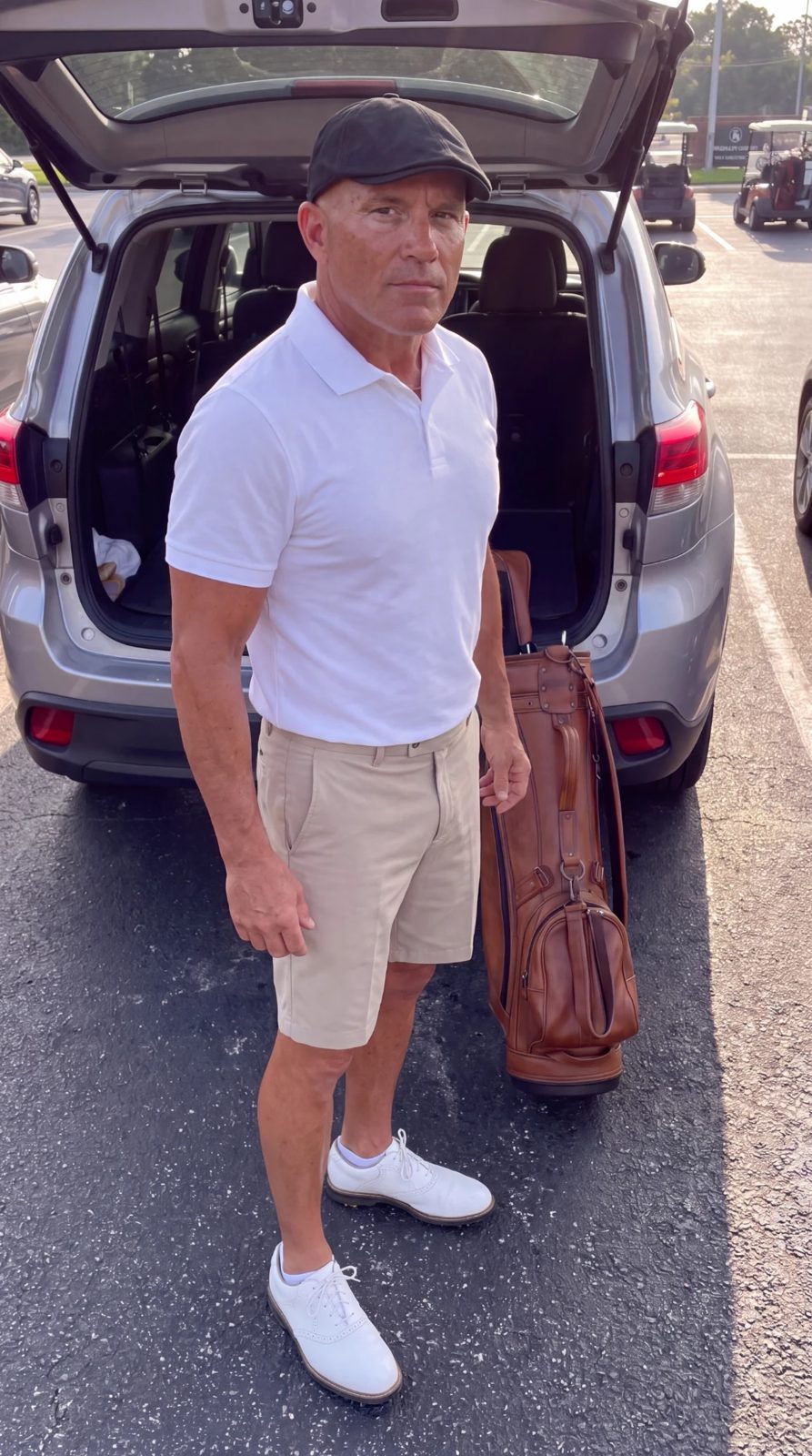 Golfer standing by his car with his leather golf bag, black flat cap