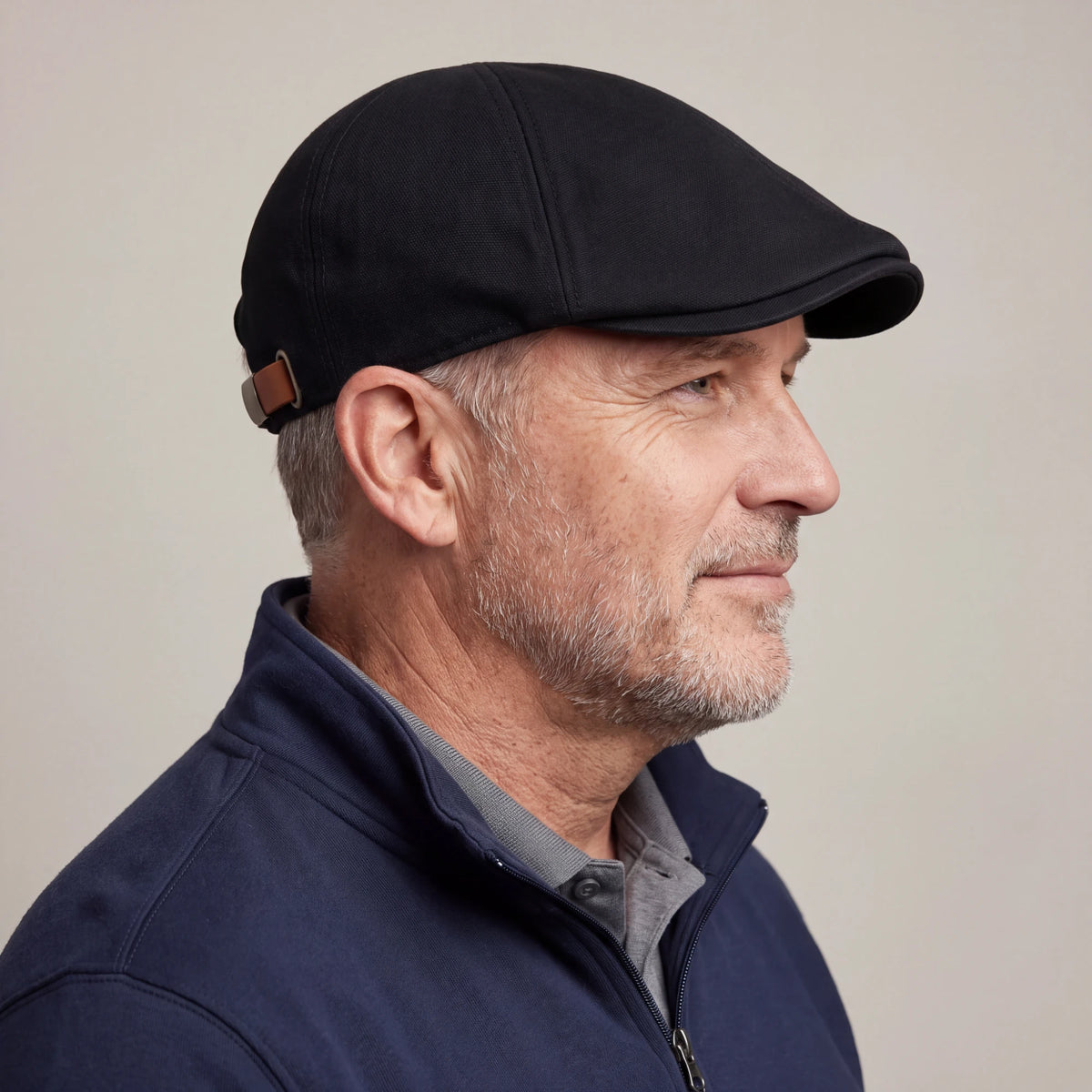Man in his late fifties wearing the black no-logo flat cap in side profile, low crown sitting close to the head