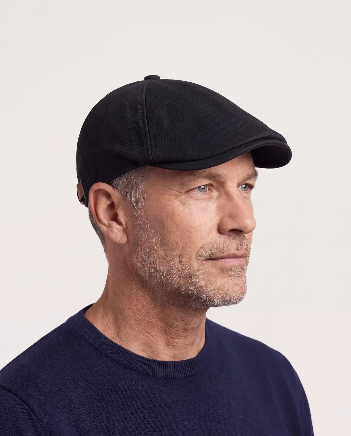 Man wearing the black flat cap pulled low, three-quarter view
