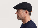 Side profile of a man wearing the black low-crown flat cap